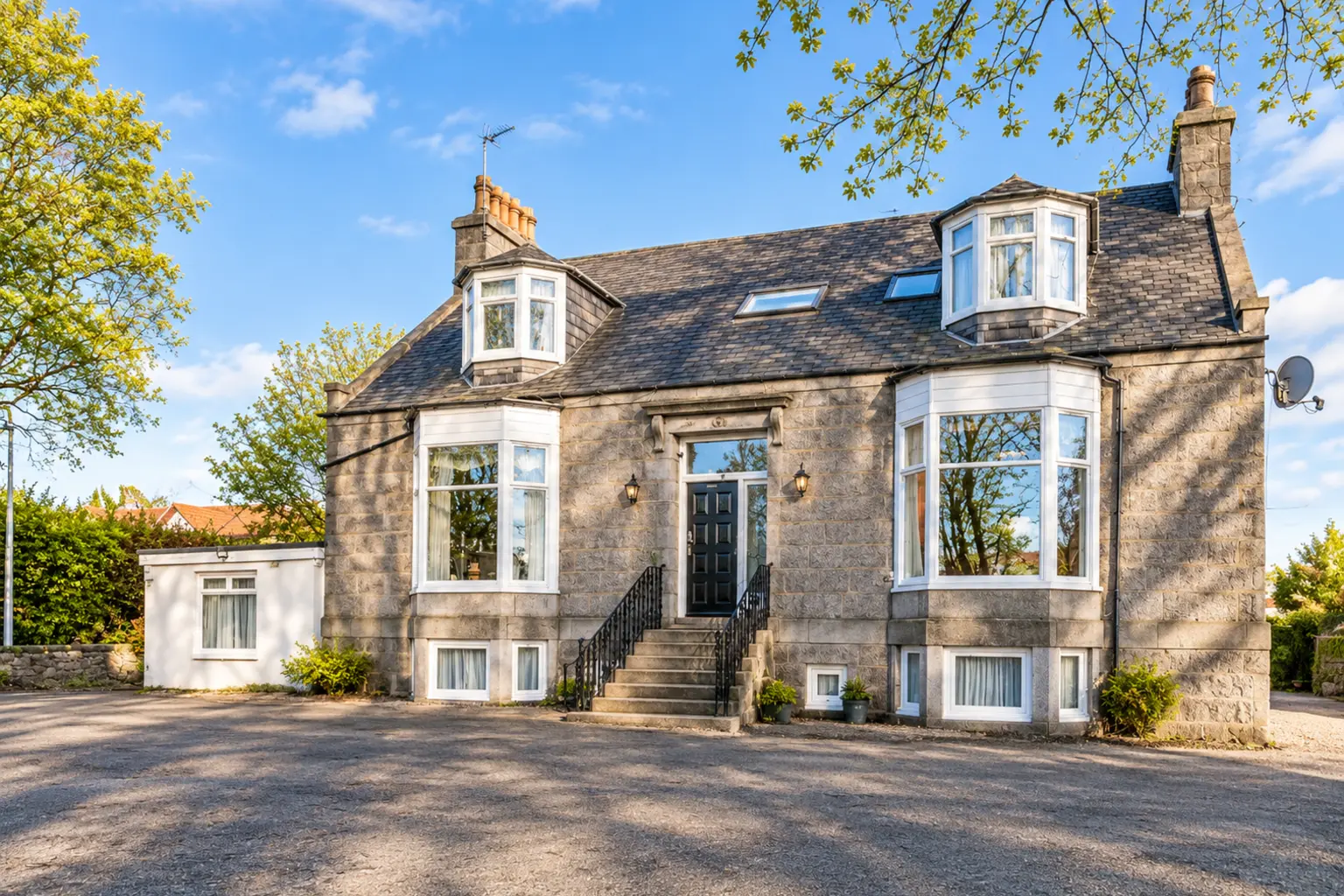 AI exterior illustration based on Station View Guest House’s official gallery: its grey granite frontage, slate roof, white bay windows, central dark door and stone steps. Not an actual photograph.